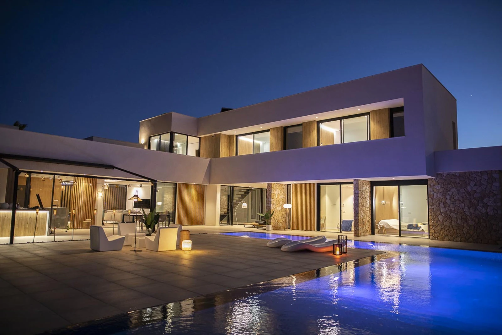 Stilvolles Privathaus mit warmer Fassadenbeleuchtung, Terrassenlicht und beleuchtetem Pool